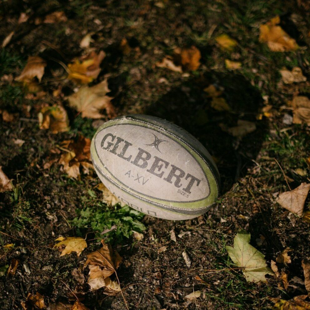 a rugby ball laying on the ground surrounded by leaves